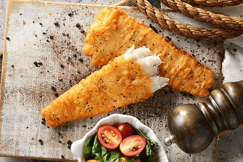 crumbed fish fillets and salad on rustic background