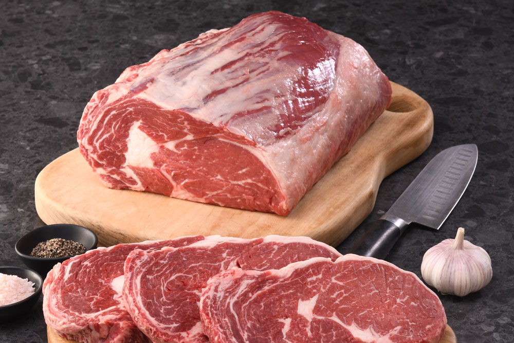 Cut of raw beef on wooden board with spice bowls