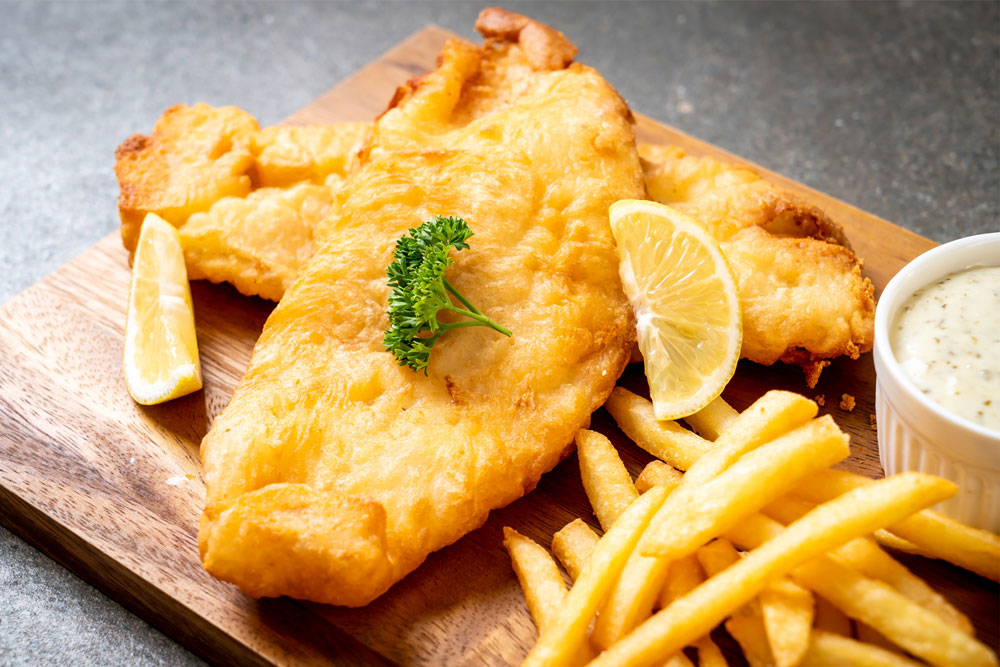 Battered fish with lemon slices, chips and aioli